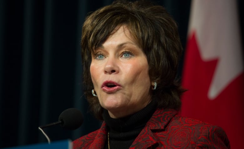 A woman speaks in front of a podium.