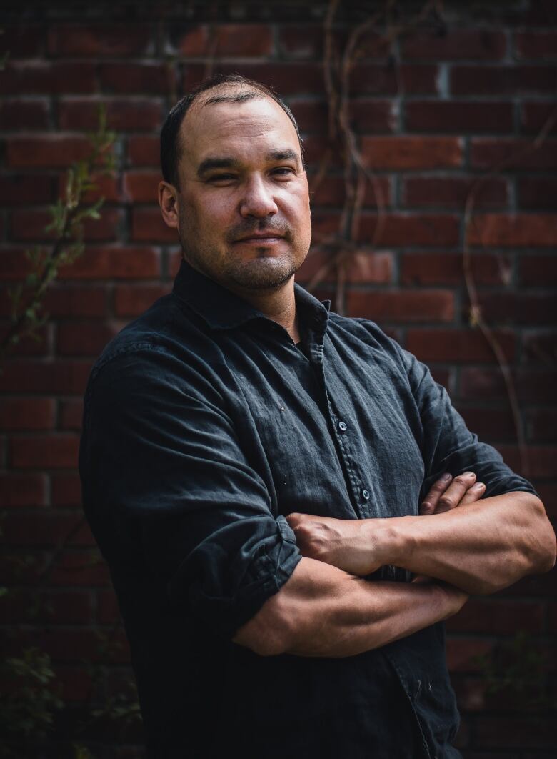 Jesse Fiddler stands in front of a brick wall.