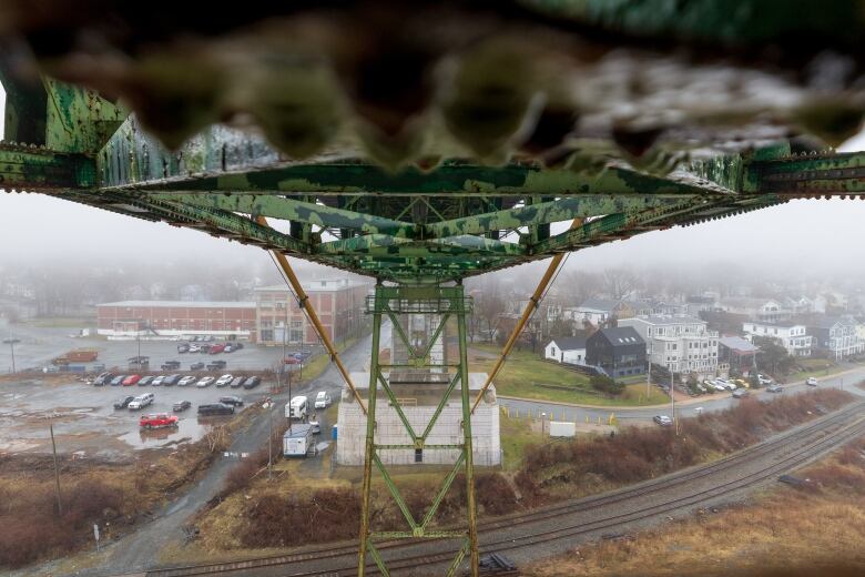 A view underneath a bridge with houses in the background on the far shore of the harbour.