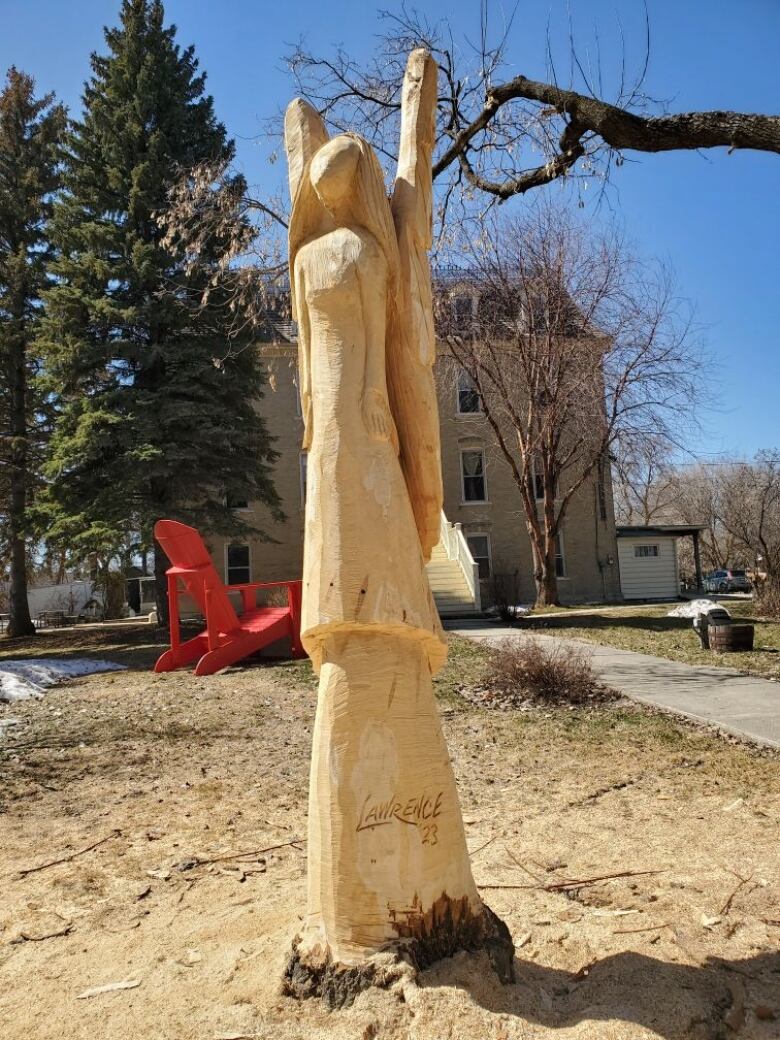 A closeup photo shows a rough wooden carving in the shape of a winged angel.