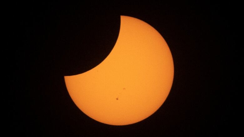 An orange moon is shown in a black sky.