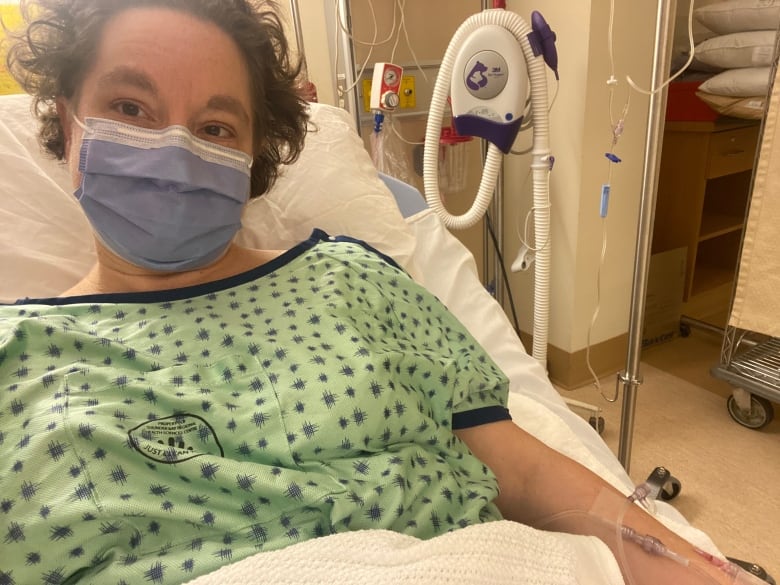 A woman lies down in a hospital with a mask over her face.