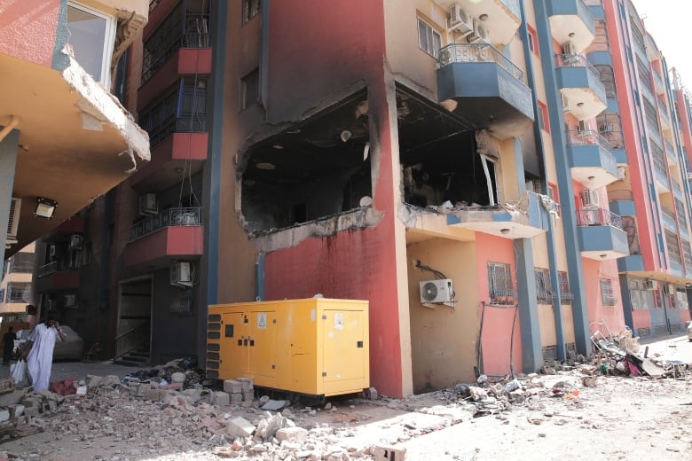 An apartment building complex is blackened. Rubble is seen laying in the street.