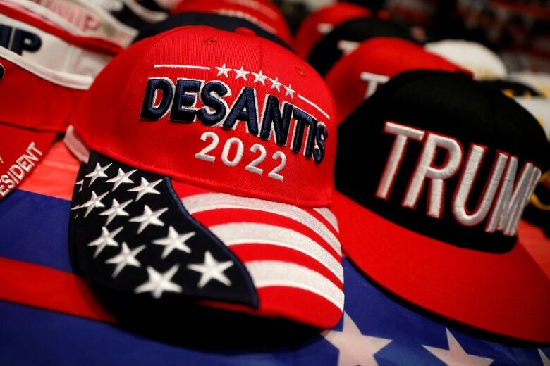 Two baseball caps. One labelled 'Trump,' the other 'DeSantis'.