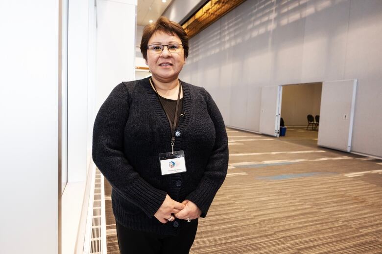 A woman wearing a lanyard is pictured in a hallway of a large convention centre.