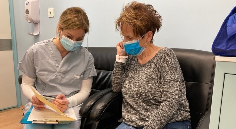 An older woman speaks to a nurse. 