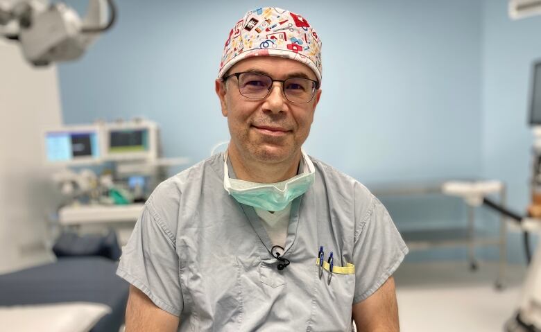 A doctors wearing a surgeon's cap smiles at the camera.