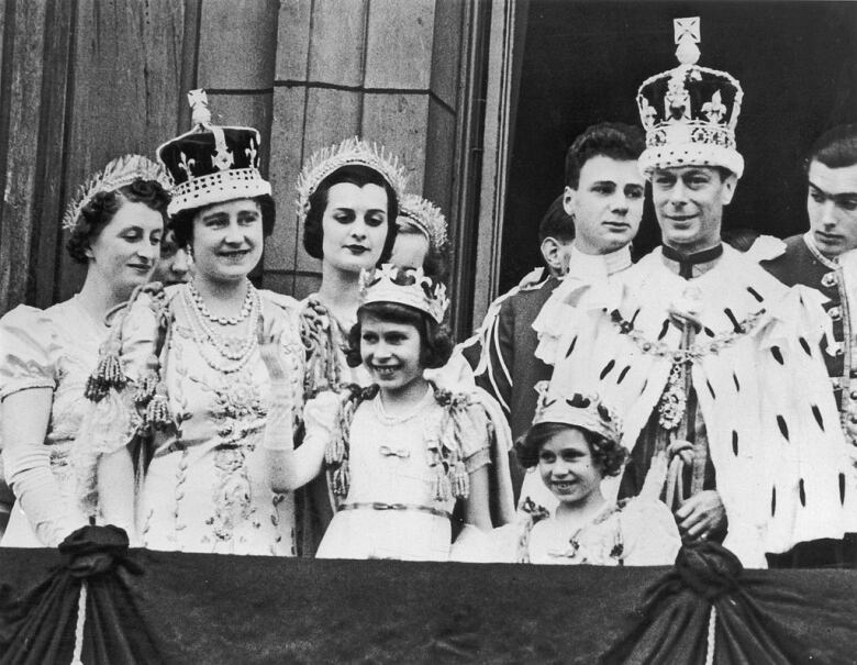 Adults wearing crowns and coronets, and two children, stand on a balcony.