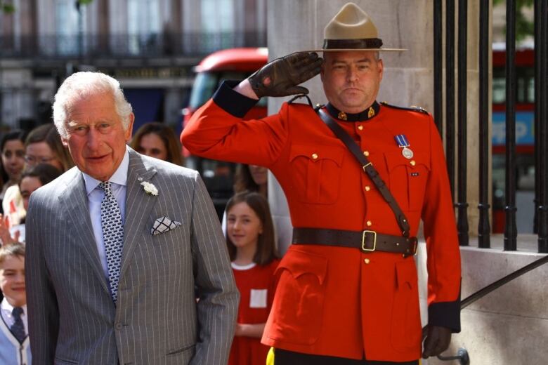 A person stands beside a Royal Canadian Mounted Police officer, who is giving a salute.