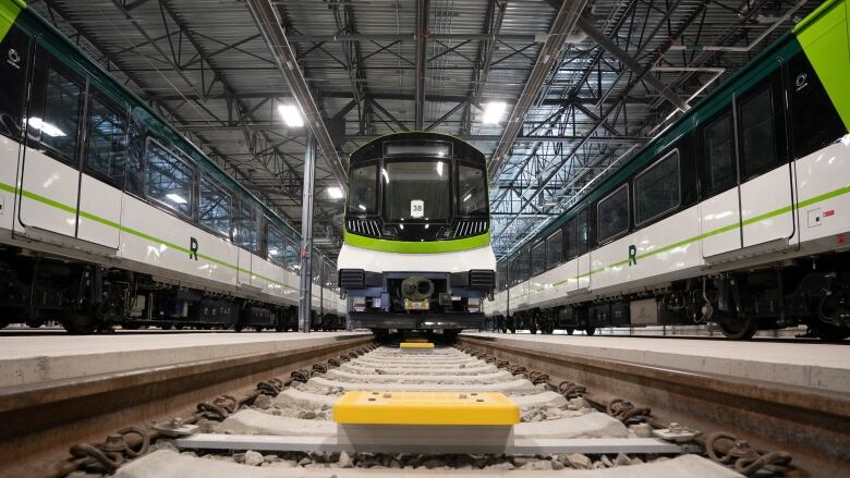 Head on shot from track level of shiny new white-and-green train.