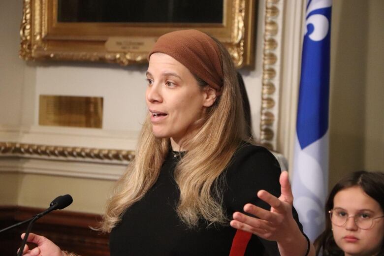 A woman stands at a podium, speaking