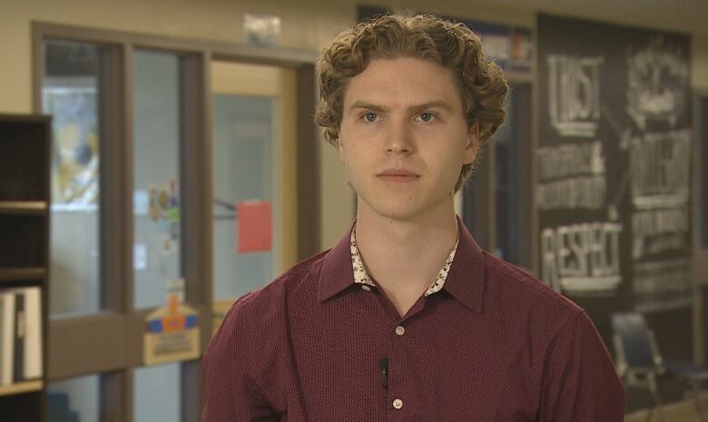 A man with sandy blond hair and blue eyes wearing a dark red shirt.