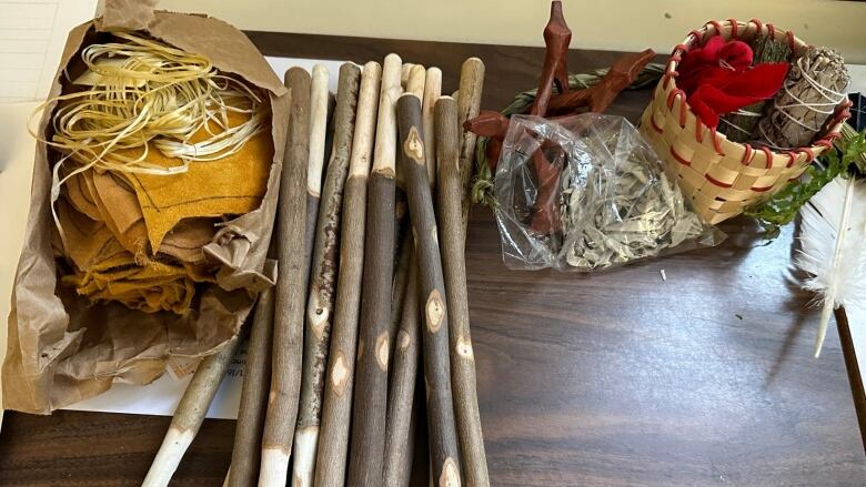 An array of drum-making materials, including sticks, lace and hide are spread out on a table.