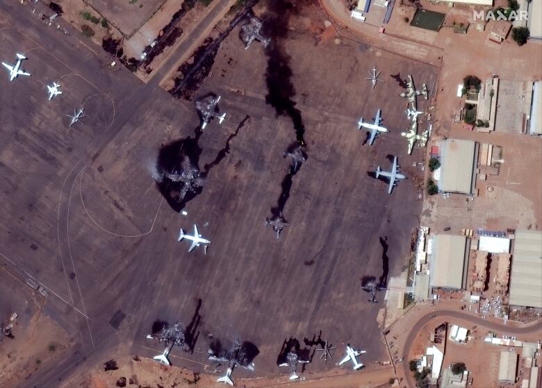 An aerial image shows several blackened, damaged airplanes on an airport tarmac