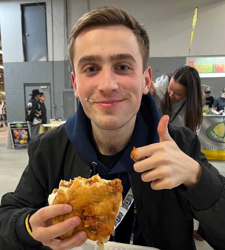 A man holding a bannock taco with a tiny bit of smeared sour cream on his right cheek