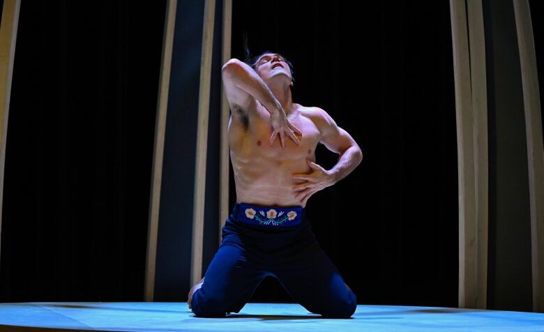 A ballet performer dances in blue with a belt with Wolastoqey florals and embellishments