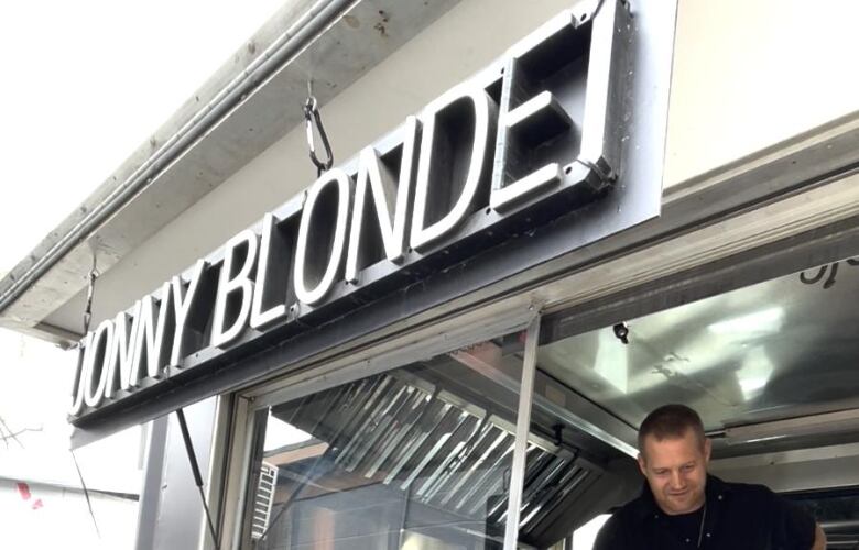 Chef Jonathan Tjerkstra stands beneath the sign for his food truck, Jonny Blonde.