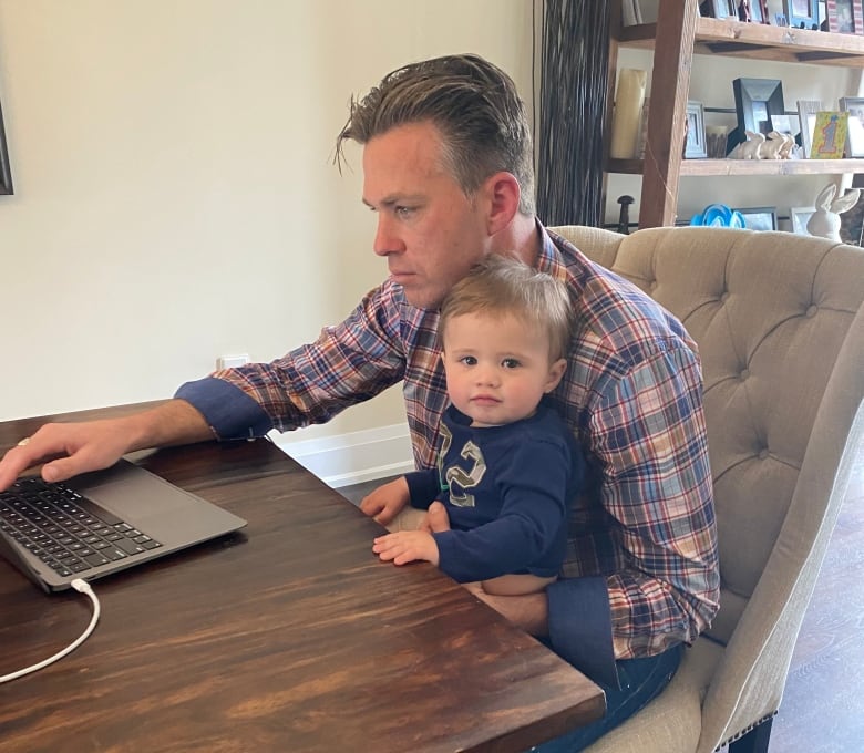 A boy sits in his dad's lap at a dinner table.