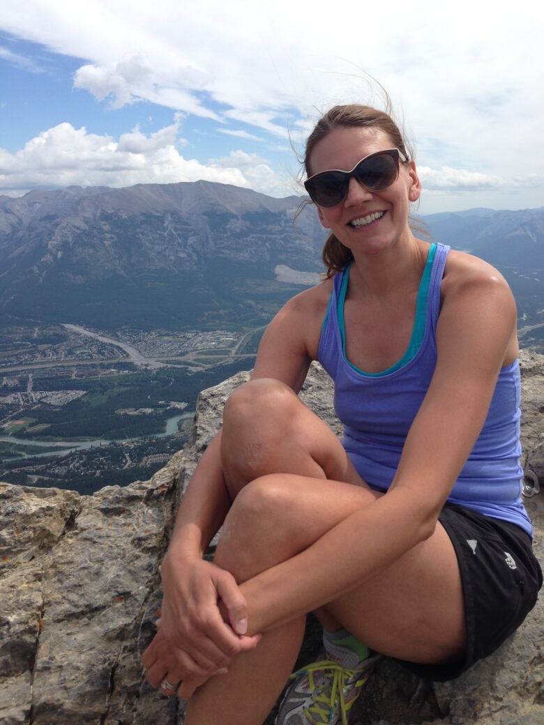 Claire Kraatz sits on a rock with a view of the mountains behind her