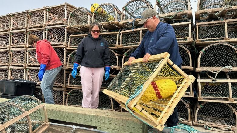 People lifting a lobster trap on a wharf