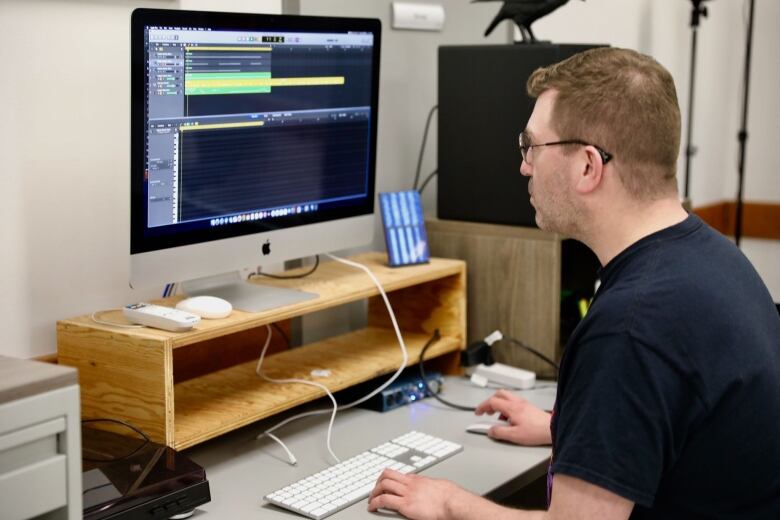 A man mixes music on a laptop. 