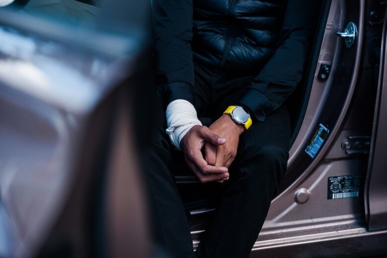 A close-up of an Indian man's bandaged hands while he is sitting in a car.