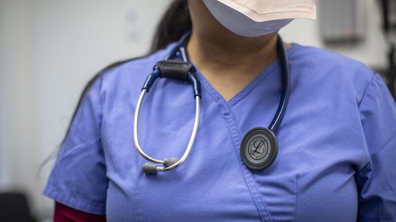 A woman in blue medical scrubs with a stethoscope around her neck. 