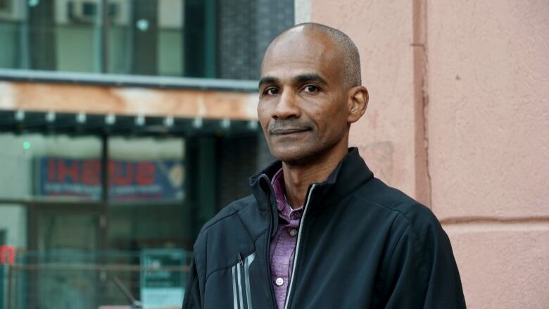 A man wearing a coat and red polo shirt.