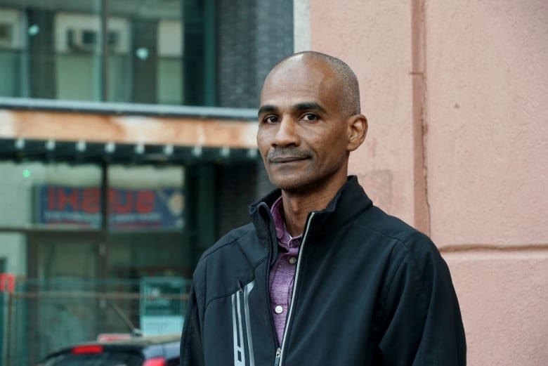 A man wearing a coat and red polo shirt.