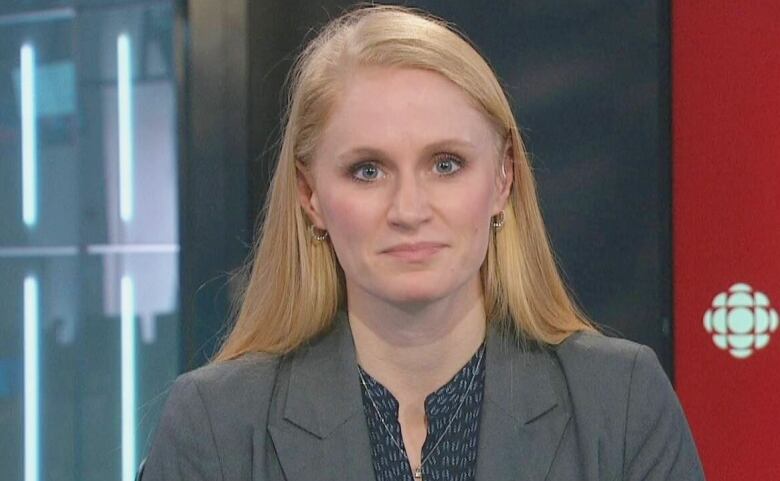 A woman with blonde hair, wearing a grey blazer, is in front of a red background, on the right, that says CBC Nova Scotia News.