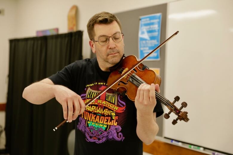 Man in colourful shirt plays the violin. 