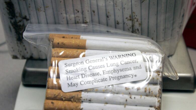 Cigarettes and a surgeon's general warning are seen in a clear plastic bag. 