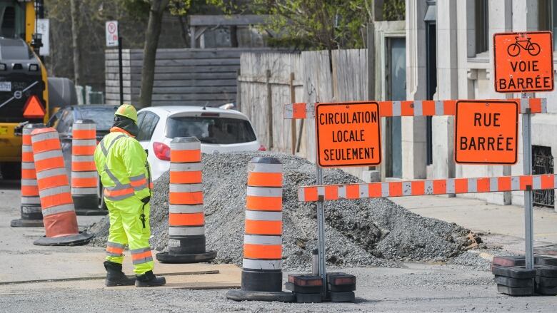 A worker is shown next to construction cones in Montreal.