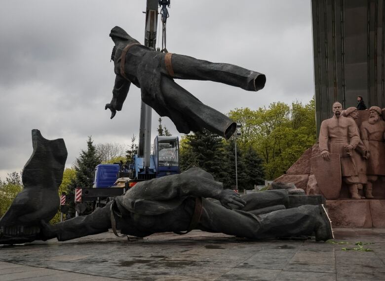 A crane lowers a piece of a statue being demolished in Kyiv, Ukraine.