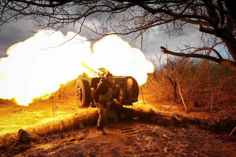 A soldier fires a howitzer.