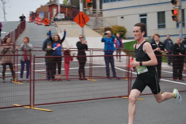 A man runs through the streets of a city with traffic lights behind him during a running race.