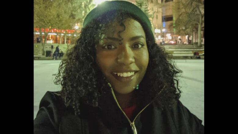 Selfie of a smiling woman with curly hair and a tuque.