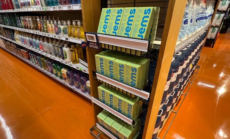 A tall narrow wooden display case full of mint green boxes of condoms with labelled in blue with the name Jems 