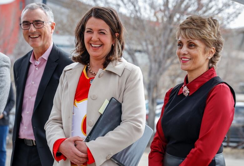 Business and political leaders smile during an outdoors announcement.