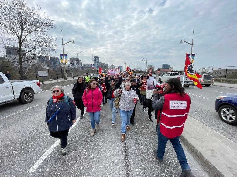 Striking workers walk on a lane of a bridge.