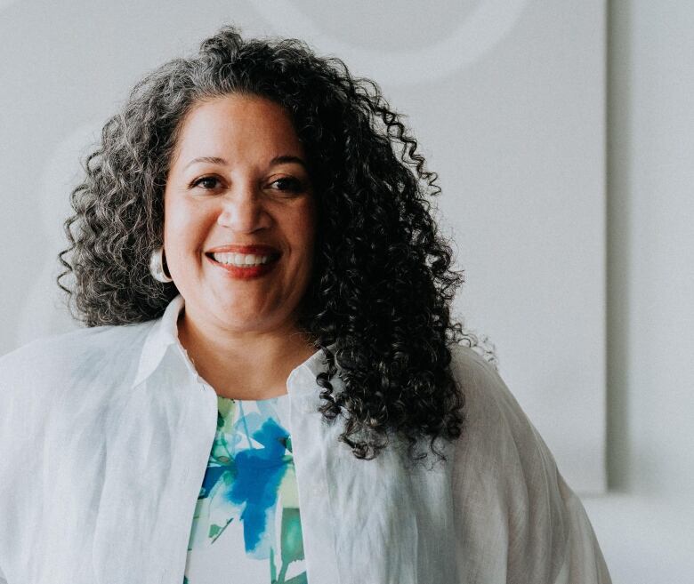 A woman with curly hair and darker skin is seen smiling. 