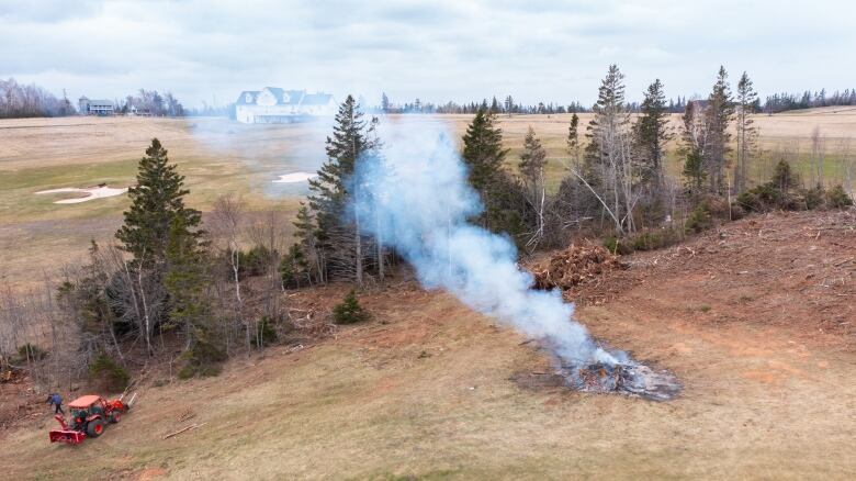 A fire burning debris from fallen trees on a golf course 