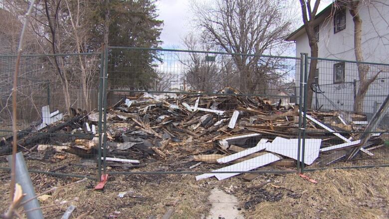 A pile of wood and metal sits behind a fence.