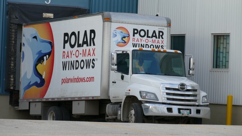 A truck with a polar bear logo is parked in loading dock. 