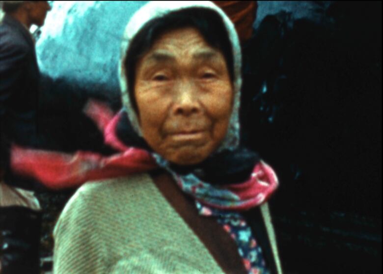 A woman with a scarf around her head is shown in an archival photograph