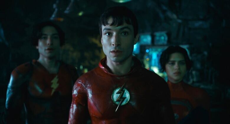 Three people wearing red superhero suits star into the camera. 