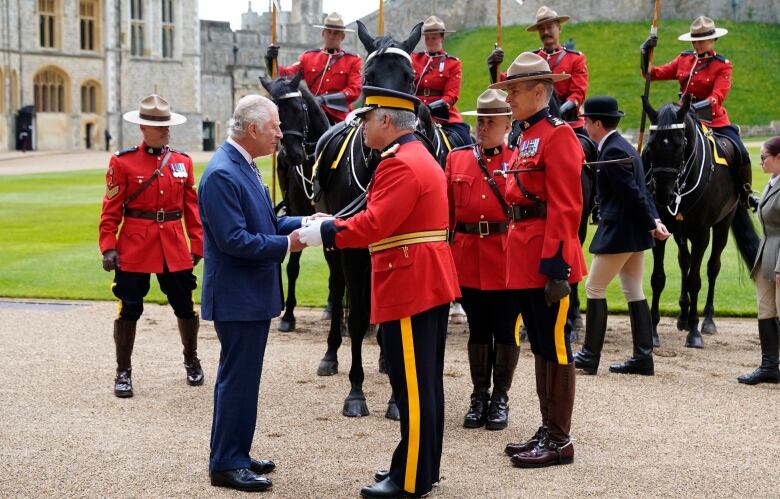 RCMP officers wearing their red serge uniforms, some on horses, present a horse to King Charles III.