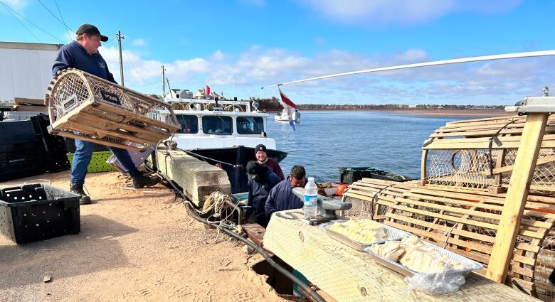 Man heaves a lobster trap onto a boat.