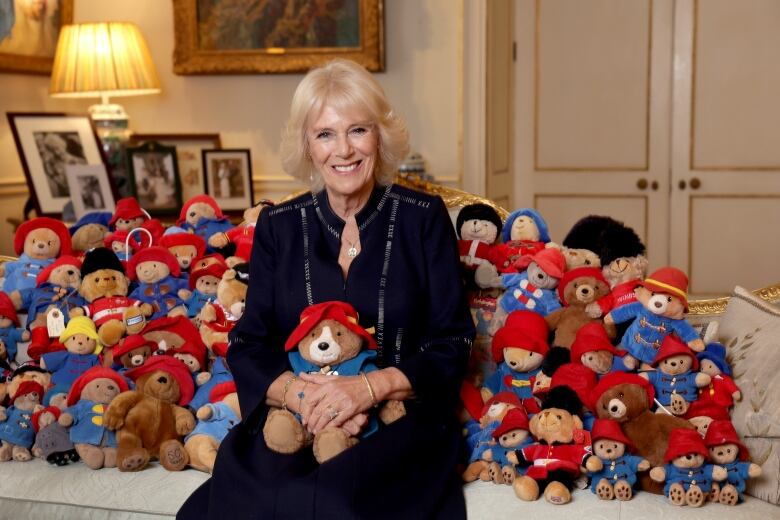 Camilla, Queen Consort,  poses at Clarence House with Paddington Bears left by admirers for Queen Elizabeth II after her death.