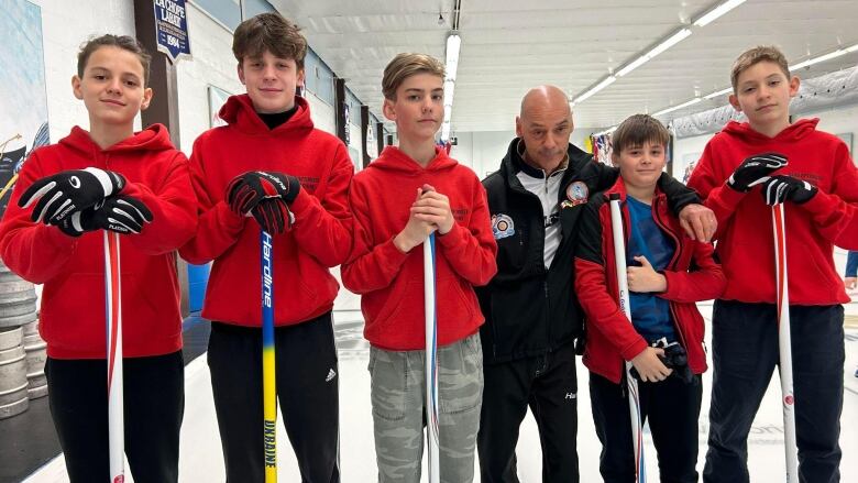 Curlers stand on the ice.